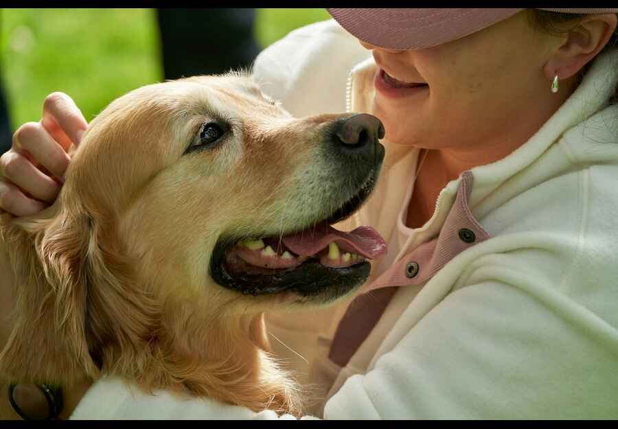 Daily Dog Bonding Moments Between Owner and Pet Woman lovingly cuddling her Golden Retriever, highlighting the importance of bonding in a daily care routine for your dog.